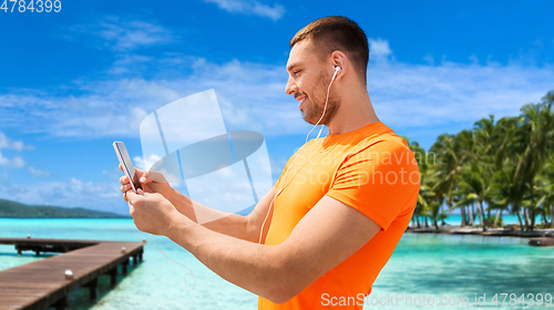 Image of smiling young man with smartphone and earphones