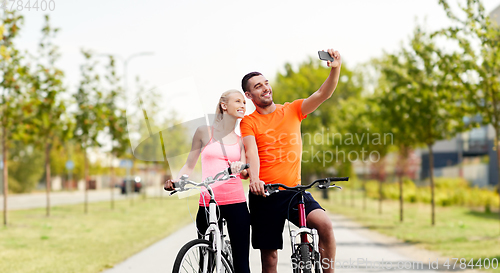 Image of couple with bicycles taking selfie by smartphone