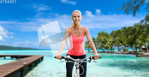 Image of happy young woman riding bicycle on beach