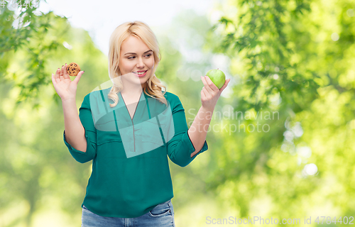 Image of smiling woman choosing between apple and cookie