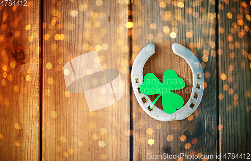 Image of horseshoe with shamrock on wooden background