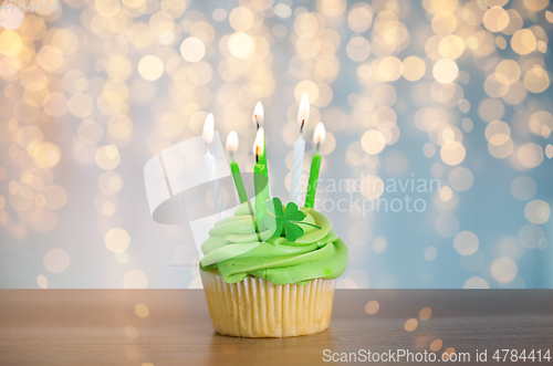 Image of green cupcake with six burning candles on table