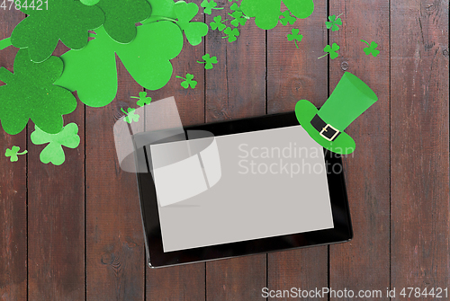 Image of tablet pc and st patricks day decorations on wood