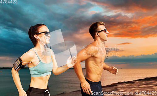 Image of couple with phones and arm bands running over sea