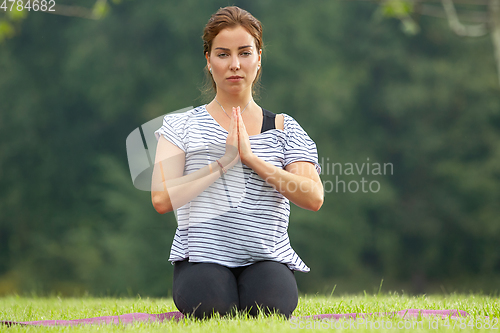 Image of Young beautiful woman doing yoga exercise in green park. Healthy lifestyle and fitness concept.