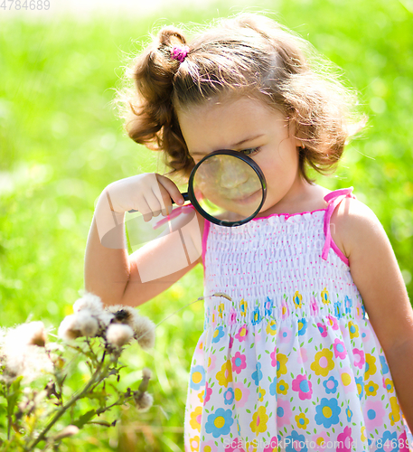 Image of Young girl is looking at flower through magnifier