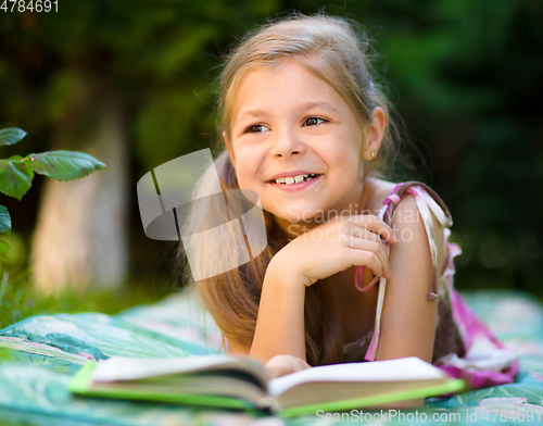 Image of Little girl is reading a book outdoors