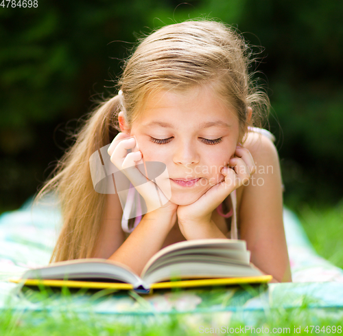 Image of Little girl is reading a book outdoors