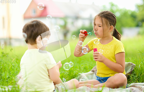 Image of Little girl and boy are blowing soap bubbles