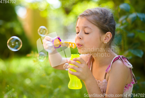 Image of Little girl is blowing a soap bubbles