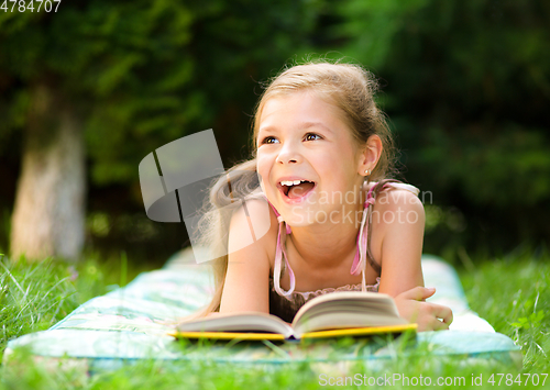 Image of Little girl is reading a book outdoors