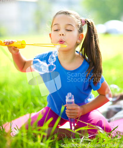 Image of Little girl is blowing a soap bubbles
