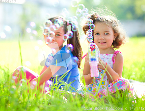 Image of Two little girls are blowing soap bubbles