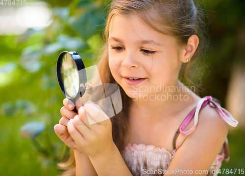 Image of Young girl is looking at flower through magnifier