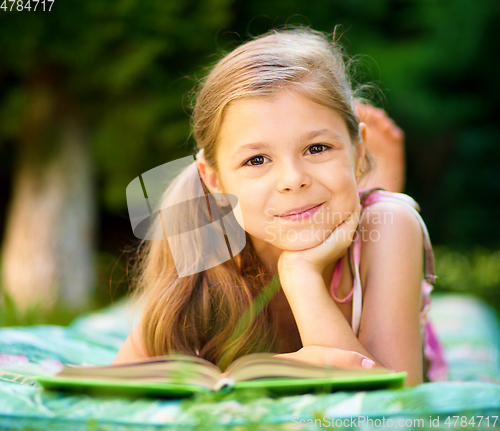Image of Little girl is reading a book outdoors