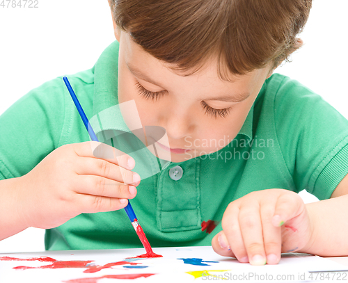 Image of Little boy is playing with paints