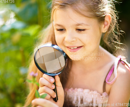 Image of Young girl is looking at flower through magnifier