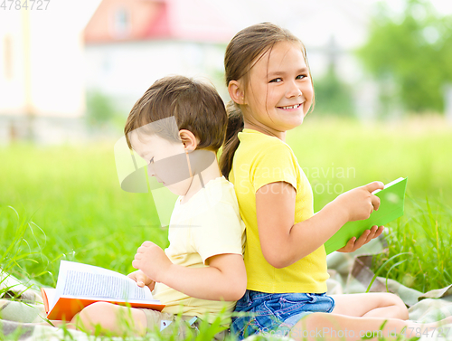 Image of Little girl and boy are reading books outdoors