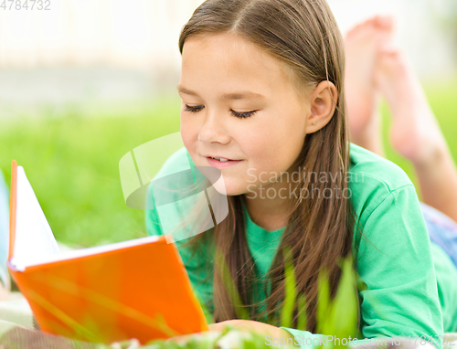 Image of Little girl is reading a book outdoors