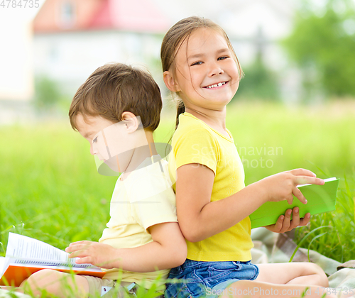 Image of Little girl and boy are reading books outdoors