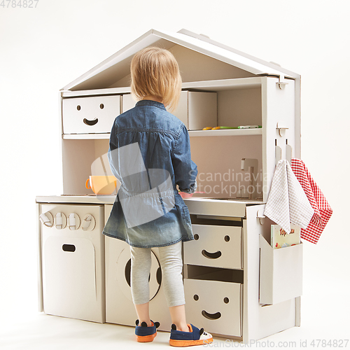 Image of toddler girl playing with toy kitchen at home