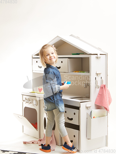 Image of toddler girl playing with toy kitchen at home