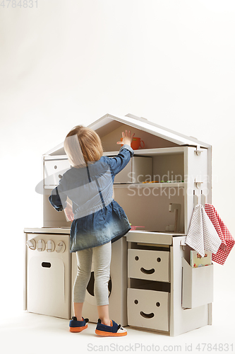 Image of toddler girl playing with toy kitchen at home