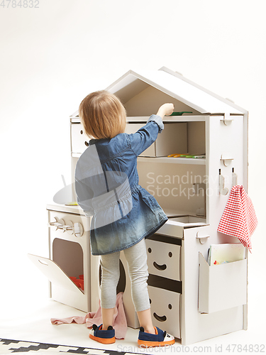 Image of toddler girl playing with toy kitchen at home