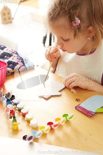 Image of Cute little girl painting on home interior background