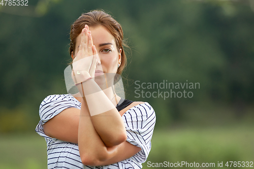 Image of Young beautiful woman doing yoga exercise in green park. Healthy lifestyle and fitness concept.