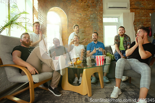 Image of Group of excited friends playing video games at home