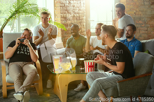 Image of Group of excited friends playing video games at home