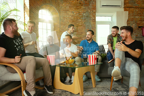 Image of Group of excited friends playing video games at home