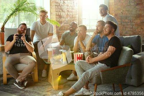 Image of Group of excited friends playing video games at home