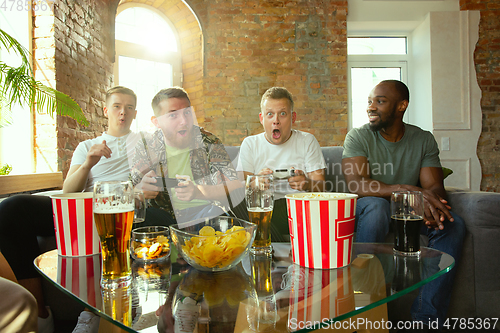 Image of Group of excited friends playing video games at home