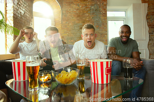 Image of Group of excited friends playing video games at home