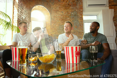 Image of Group of excited friends playing video games at home