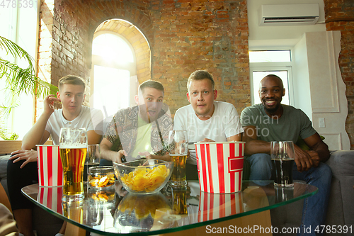 Image of Group of excited friends playing video games at home