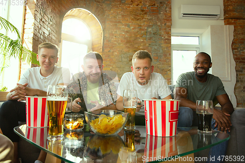 Image of Group of excited friends playing video games at home