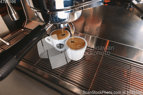 Image of Stylish black espresso making machine brewing two cups of coffee, shooted in cafe.