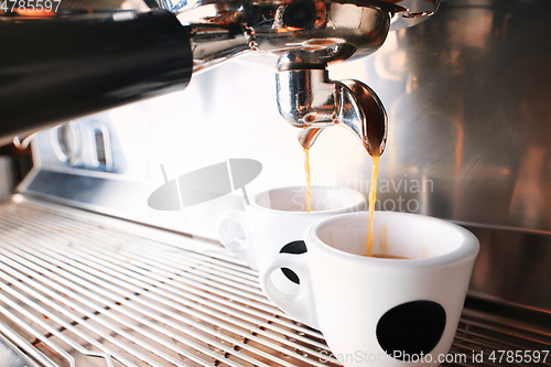 Image of Stylish black espresso making machine brewing two cups of coffee, shooted in cafe.