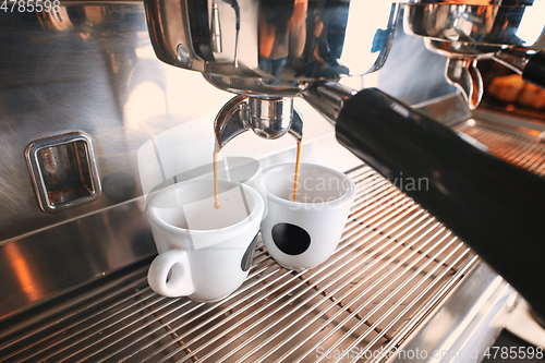 Image of Stylish black espresso making machine brewing two cups of coffee, shooted in cafe.