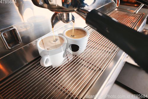 Image of Stylish black espresso making machine brewing two cups of coffee, shooted in cafe.