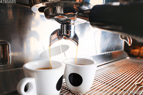 Image of Stylish black espresso making machine brewing two cups of coffee, shooted in cafe.