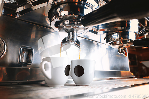 Image of Stylish black espresso making machine brewing two cups of coffee, shooted in cafe.