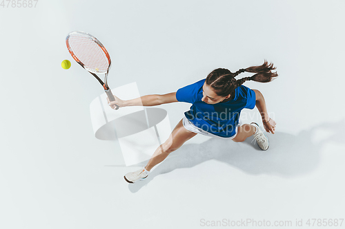 Image of Young woman in blue shirt playing tennis. Youth, flexibility, power and energy.