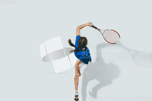 Image of Young woman in blue shirt playing tennis. Youth, flexibility, power and energy.