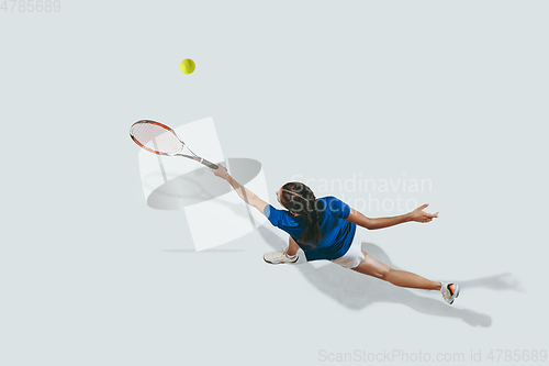 Image of Young woman in blue shirt playing tennis. Youth, flexibility, power and energy.