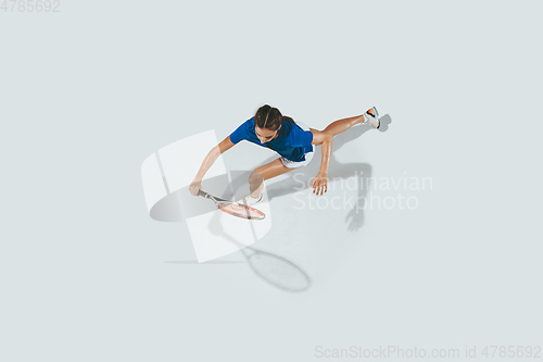 Image of Young woman in blue shirt playing tennis. Youth, flexibility, power and energy.