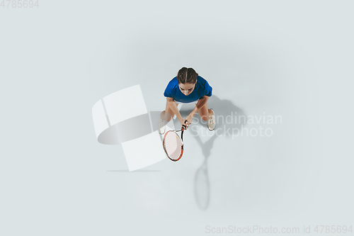 Image of Young woman in blue shirt playing tennis. Youth, flexibility, power and energy.